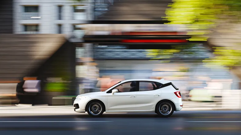 White fleet hatchback driving through the city
